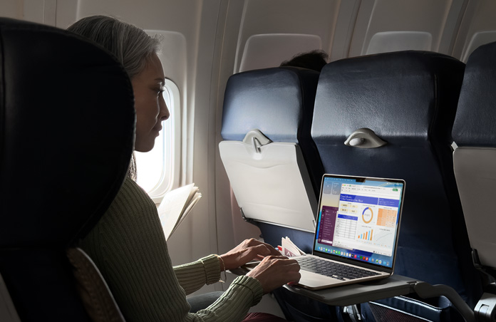 Osoba sedící na sedadle v letadle pracuje na MacBooku Air